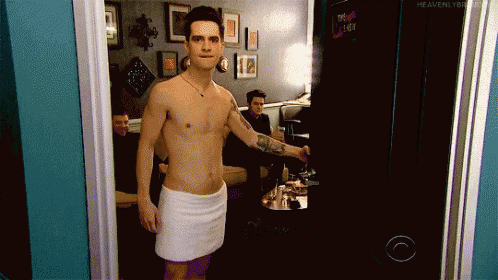 a shirtless man with a towel around his waist is standing in front of a tv screen that says heavenly boy