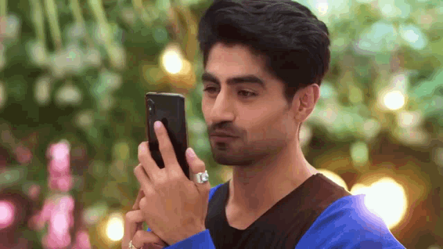 a man in a blue shirt is looking at his phone