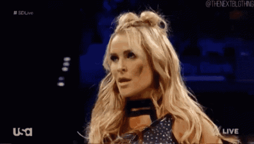 a blonde woman with two buns in her hair is standing in a dark room .