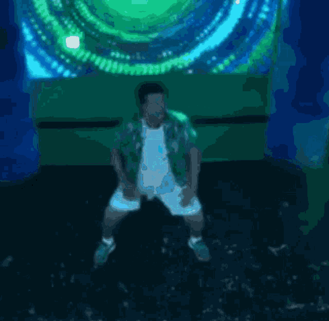 a man in a green shirt and white shorts is dancing in front of a green screen