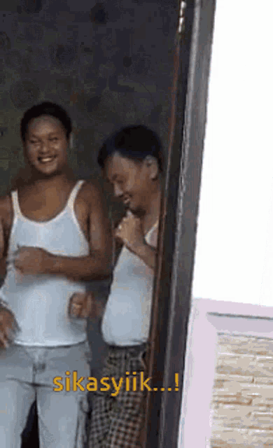 two men are standing next to each other in a room and one of them says " sikasyiik ... "