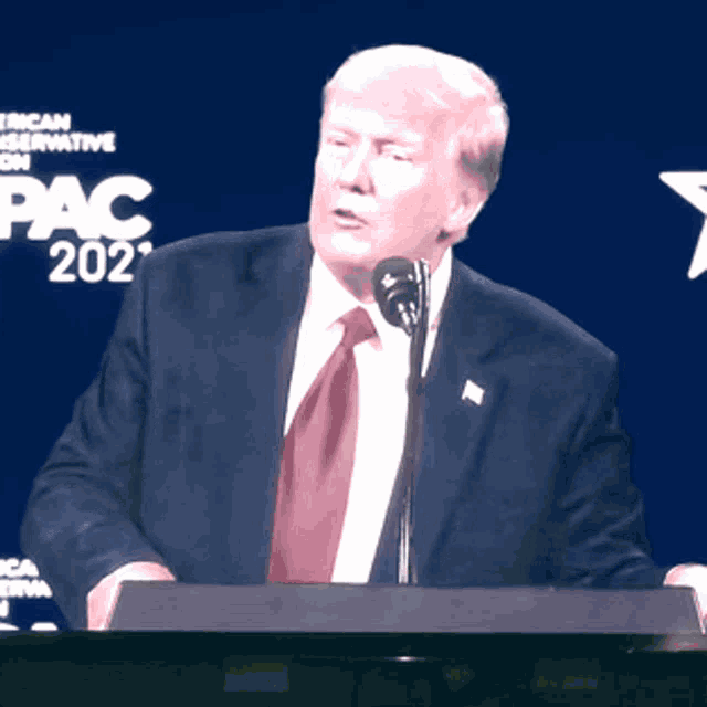 donald trump stands at a podium speaking into a microphone at pac 2021