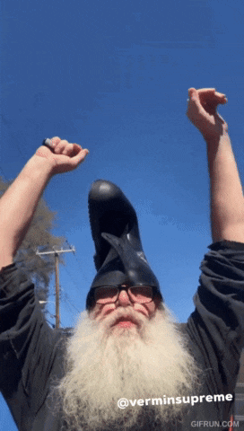 a man with a beard is wearing a helmet with a shark head on it