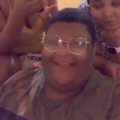 a group of people are posing for a picture and one of them is wearing glasses and giving the middle finger .
