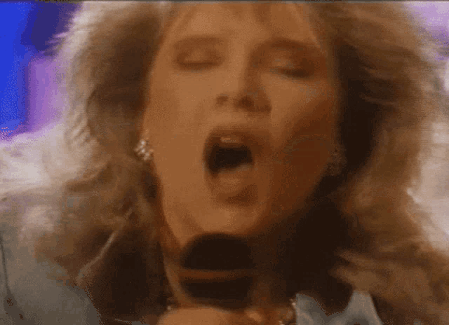 a woman is singing into a microphone with her mouth open