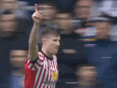 a man in a red and white striped jersey is giving the middle finger