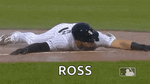 a baseball player is laying on the ground on the base .