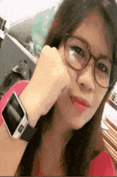 a young woman wearing glasses and a smart watch on her wrist .