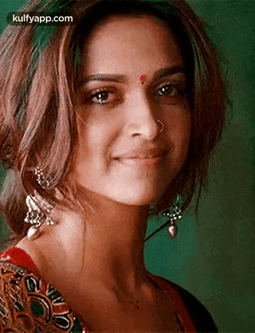 a close up of a woman wearing a nose ring and earrings smiling .