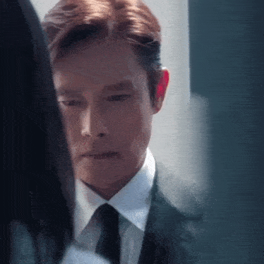 a man in a suit and tie is looking at another man .
