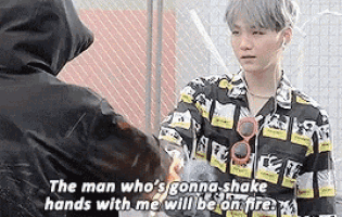 a man is shaking hands with another man and says `` the man who 's gonna shake hands with me will be on fire . ''