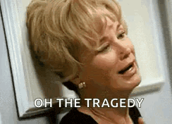 a woman is crying and leaning against a wall with the words `` oh the tragedy '' written on her face .
