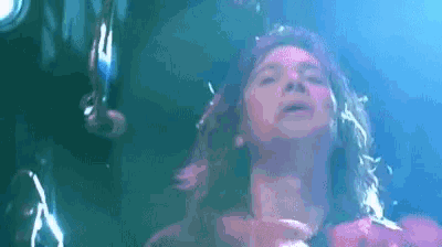 a woman with long hair is singing into a microphone on a stage in front of a crowd .
