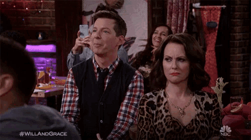 a man in a plaid shirt is smiling while a woman in a leopard print dress looks on