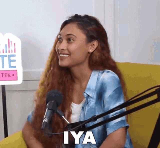 a woman is sitting in front of a microphone with the word iya on her face