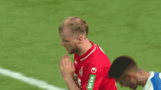 a soccer player wearing a red shirt with a green patch that says deva on it