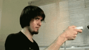 a man is holding a wii controller in front of a window with blinds