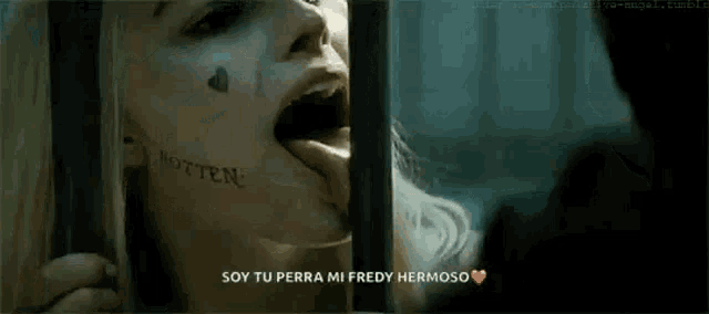 a woman with a tattoo on her face is biting a man 's finger .