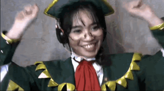 a woman wearing a green hat and headphones is smiling and raising her hands in the air