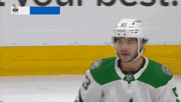 a hockey player with the number 53 on his helmet stands on the ice