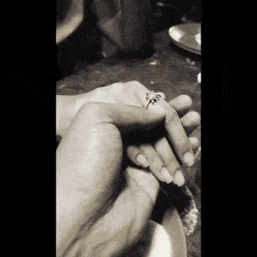 a black and white photo of a man and woman holding hands