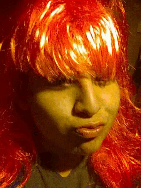 a close up of a person 's face with a red wig
