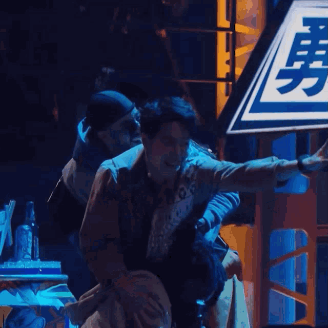 two men are standing in front of a sign with chinese writing