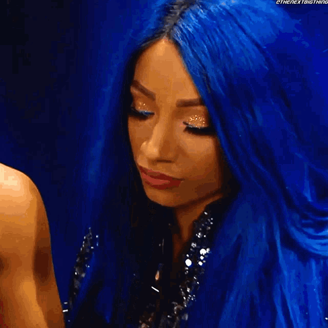 a woman with blue hair and pink lipstick is looking down at something .