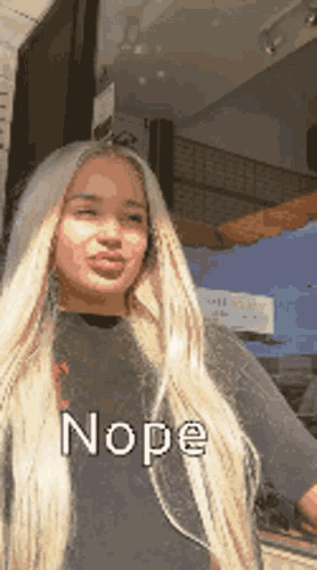 a woman with long blonde hair is wearing a black shirt that says nope