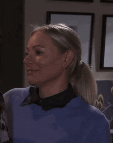 a woman in a blue sweater is smiling and looking at another woman