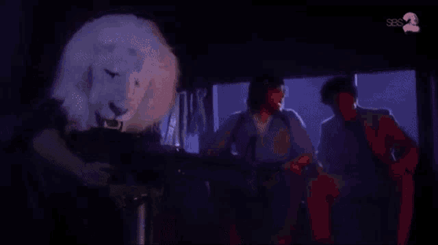 a man in a lion mask is holding a gun in a dark room