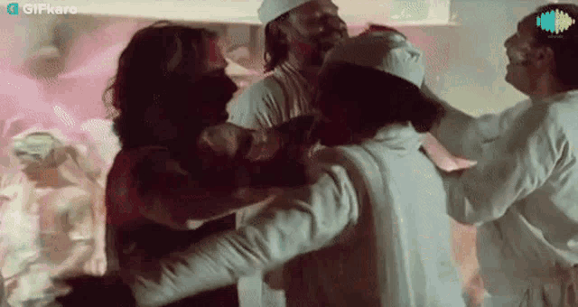 a group of men are hugging each other in a room with a pink background .