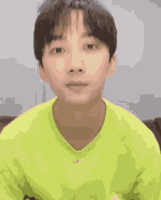 a close up of a person 's face with their eyes closed and wearing a green shirt .