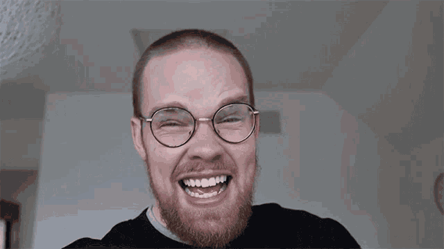 a man with glasses is covering his mouth with his hands
