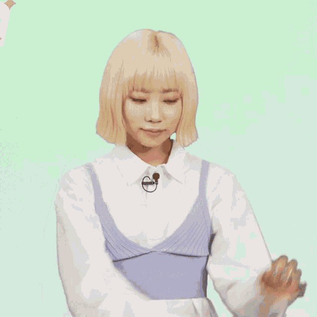a woman with blonde hair is wearing a white shirt and a purple tank top