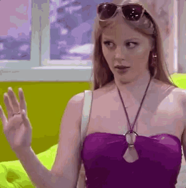 a woman wearing sunglasses and a purple top is waving
