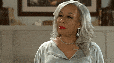 a woman with gray hair and red lipstick is wearing earrings and a necklace