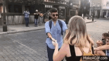 a man is shaking hands with a woman on a street while a band plays in the background .
