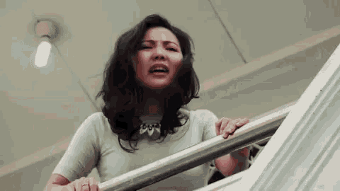 a woman is crying while holding onto a railing .