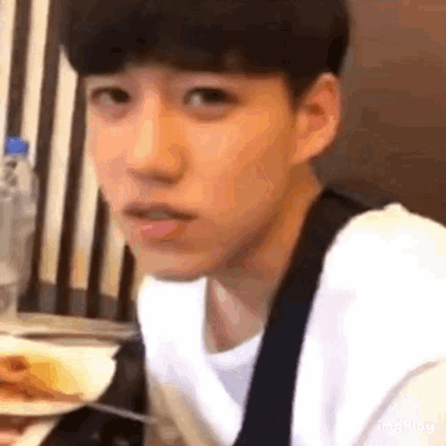 a young man is sitting at a table with a plate of food and a fork .