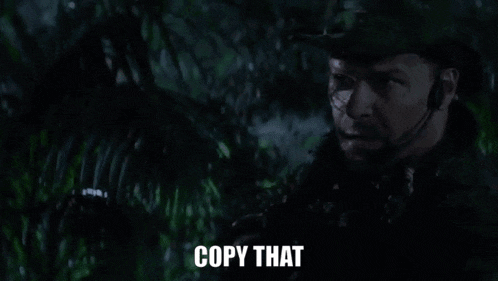 a man in a military uniform is standing in the jungle at night and says `` copy that '' .
