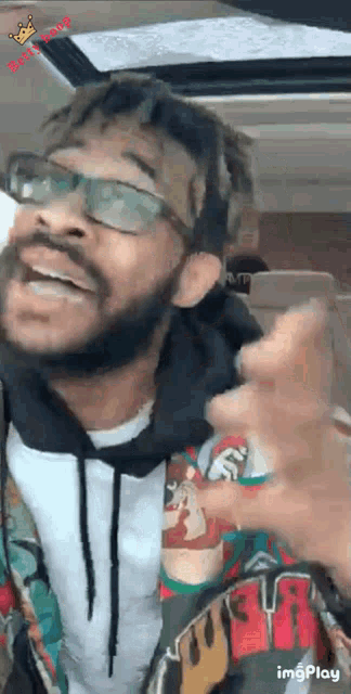 a man with glasses and a beard is laughing and pointing