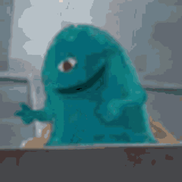 a blue stuffed animal is sitting on top of a pile of sand .
