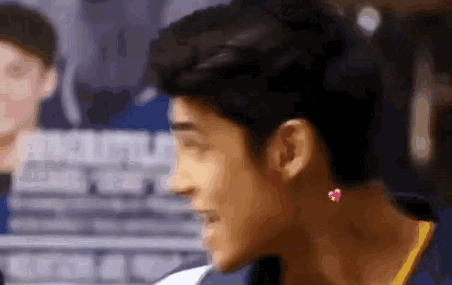 a close up of a person 's face with a pink heart earring .