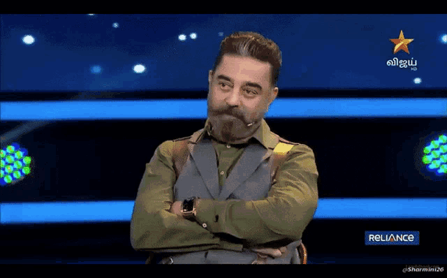 a man with a beard is on a television screen with a reliance logo