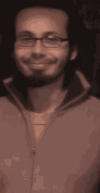 a man with glasses and a beard is smiling and looking at the camera .