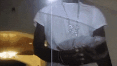 a person wearing a white shirt and a necklace is standing in front of a glass wall