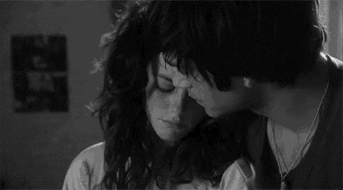 a black and white photo of a man and woman hugging each other .