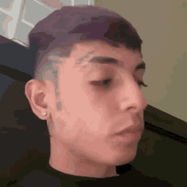 a young man with purple hair and a tattoo on his face