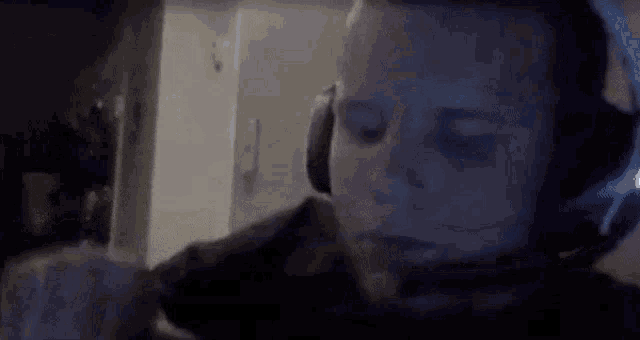 a man wearing headphones and a headset is looking at a computer screen .